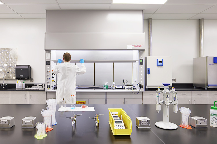 Man in lab coat facing lab equipment