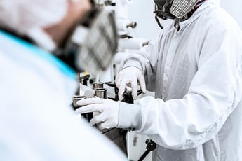 People in lab coats and masks on assembly line